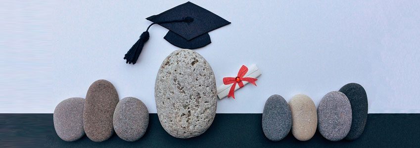 A group of stones, with one wearing a graduation cap